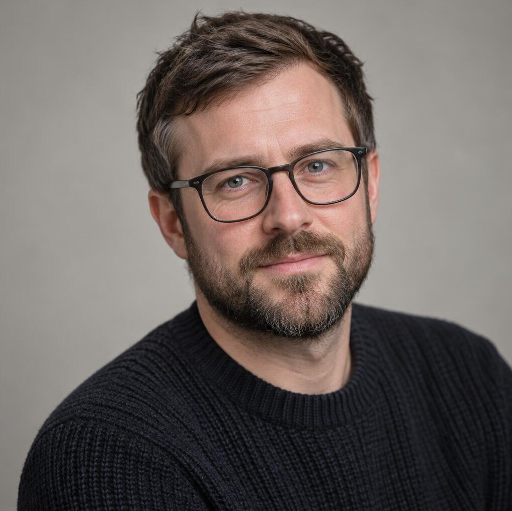 Portrait of a man with glasses and a short beard in a sweater