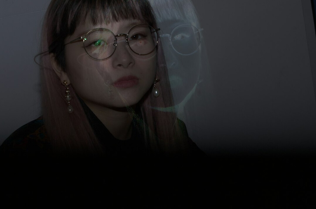 Woman with glasses concentrating on a computer monitor in a dim control room
