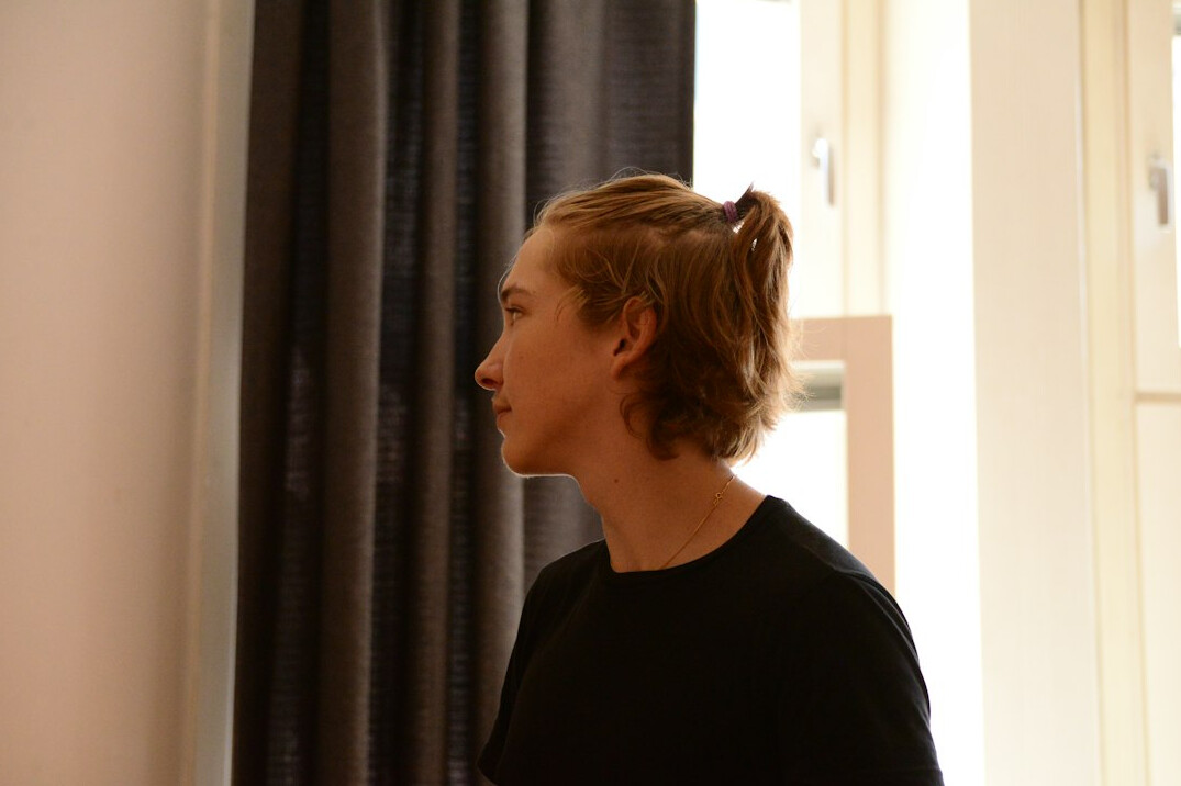 Portrait of a young woman with blonde hair tied back wearing a black top
